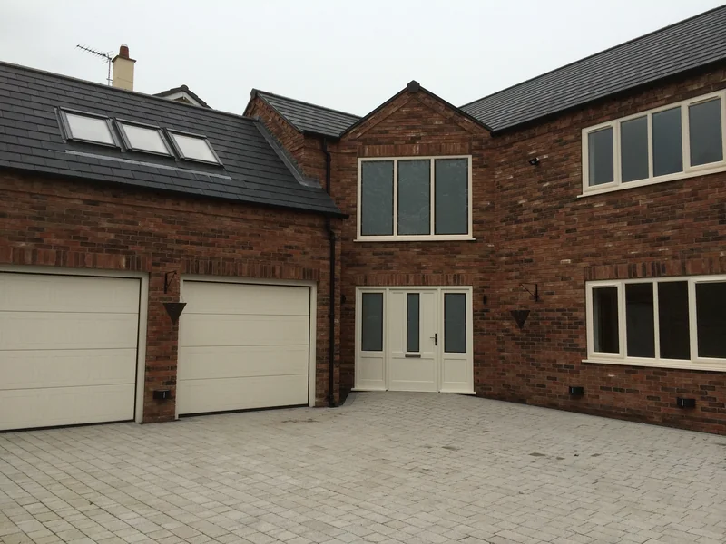Two white garage doors on a large brick house