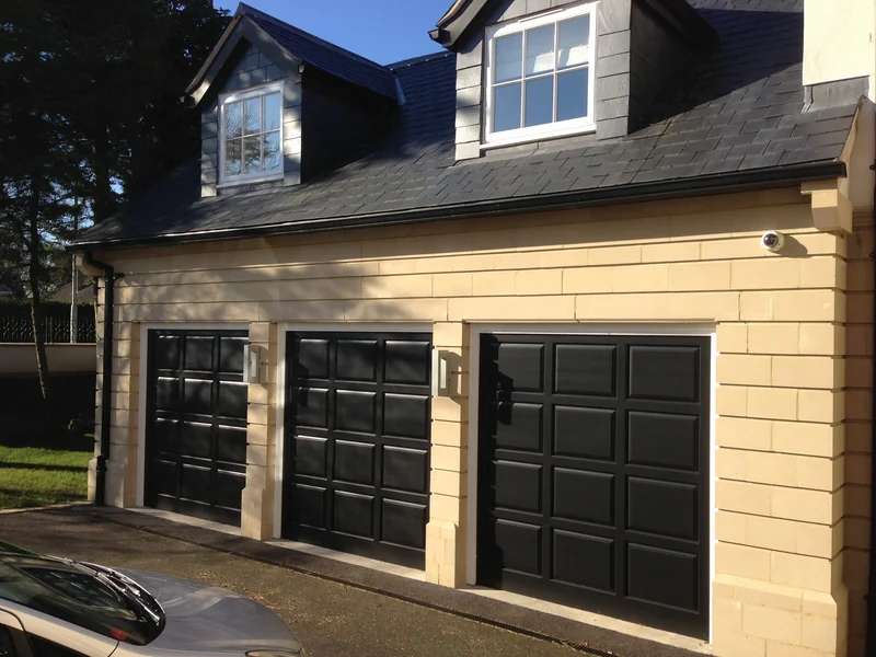 Three black sectional garage doors on a detached house