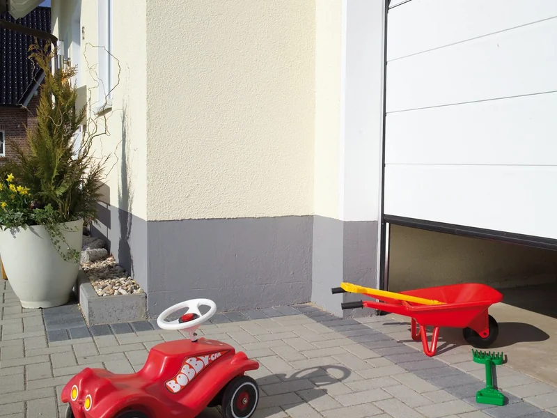 Toys on the driveway in front of an automatic garage door